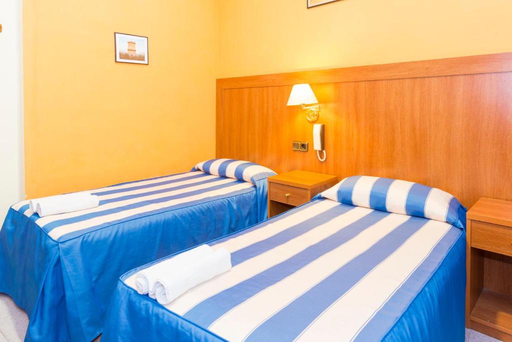 巴塞罗那珊瑚膳食公寓的酒店客房内设有两张蓝色和白色的床。