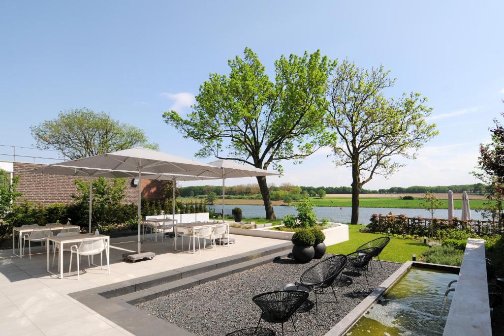 凯瑟尔Het Raadhuys - design B&B的一个带椅子和遮阳伞的庭院和一个池塘