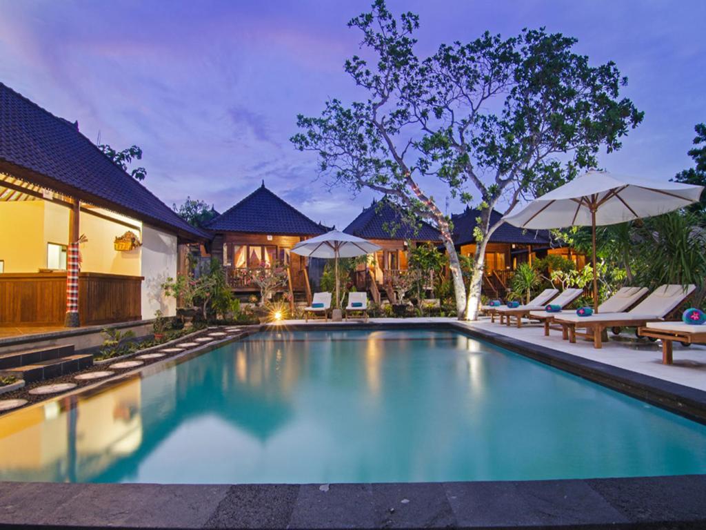 蓝梦岛卡萨哇简易别墅酒店的房屋旁的游泳池配有椅子和遮阳伞