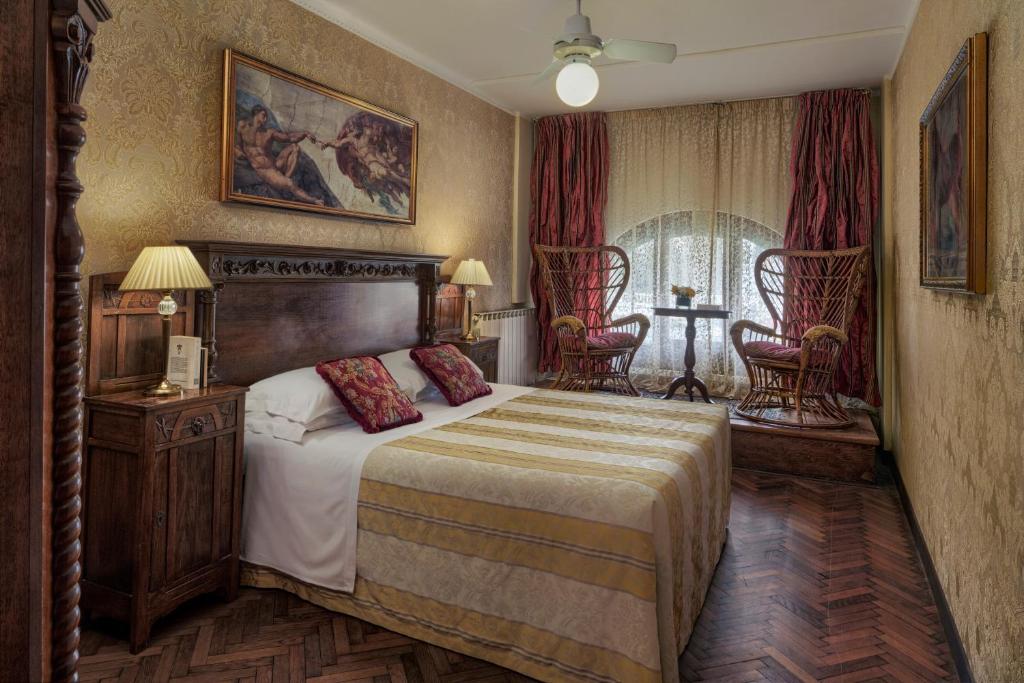 威尼斯加勒里亚酒店的一间卧室配有一张大床和两把椅子