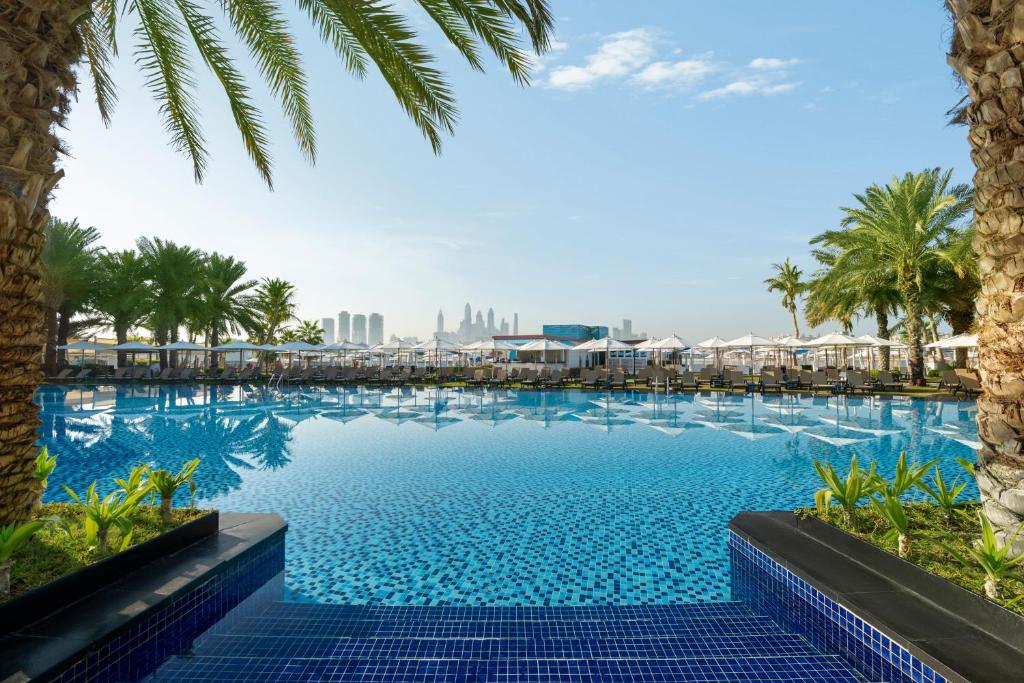 迪拜Rixos The Palm Hotel &amp; Suites - Ultra All Inclusive的一座棕榈树和建筑的大型游泳池
