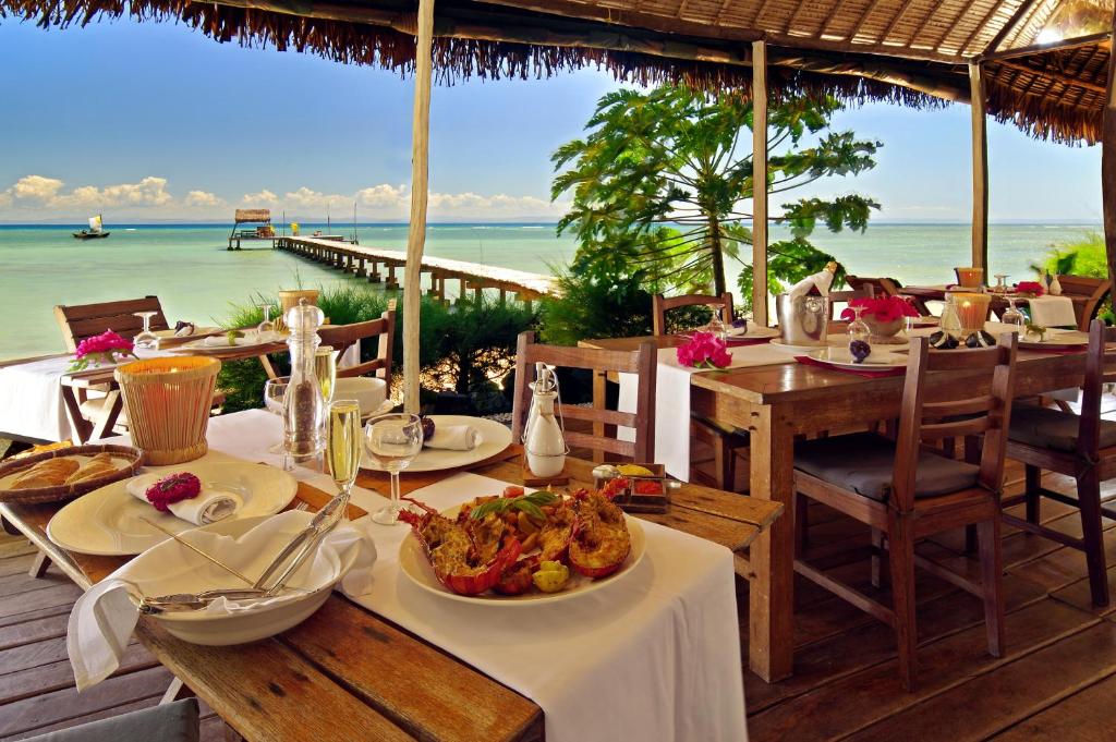 圣玛丽Villas de Vohilava的餐厅设有一张带食物的桌子,享有海景