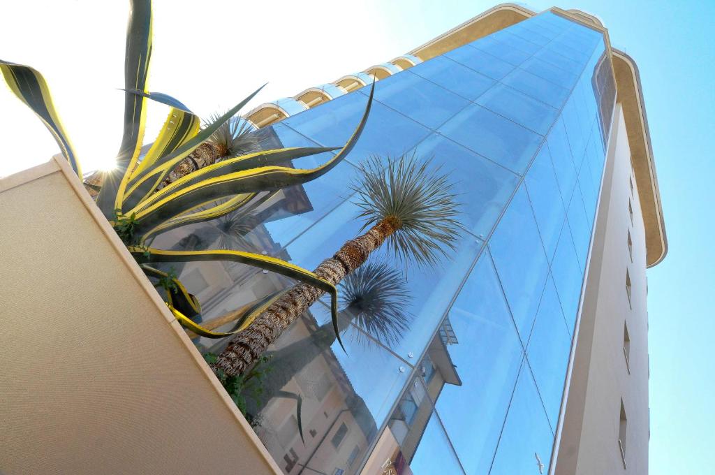 格拉多Suite & Spa Mirabel的一座高大的玻璃建筑,前面有一棵棕榈树