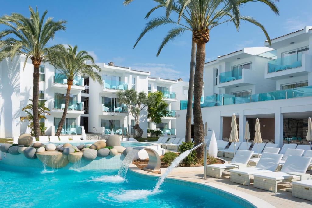波连萨港MarSenses Puerto Pollensa Hotel & Spa的一座拥有游泳池和棕榈树的酒店