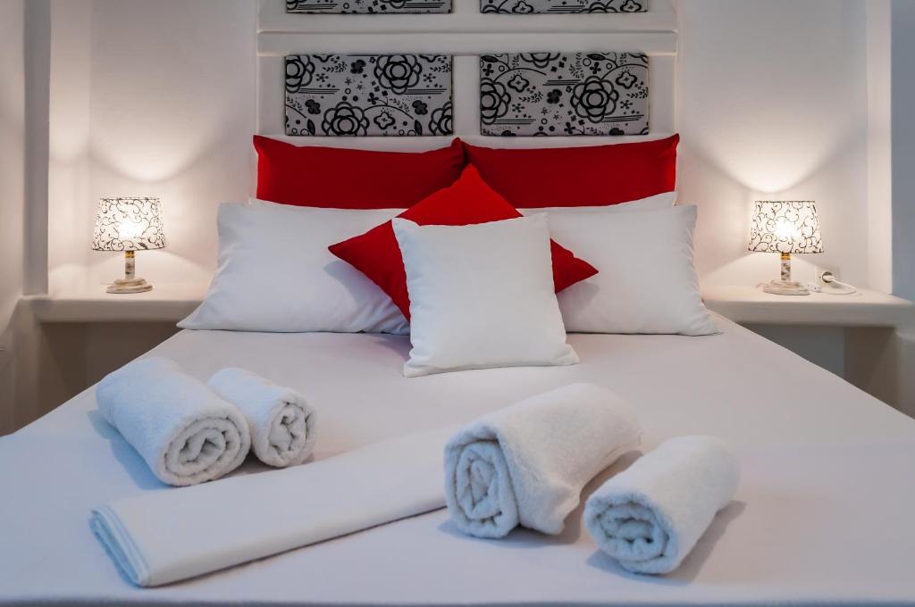 阿达玛斯Oceanis Rooms的卧室配有白色床和红色及白色枕头