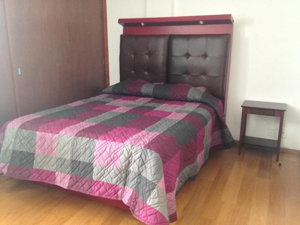 墨西哥城市区美丽公寓的一间卧室配有一张带粉红色和灰色被子的床