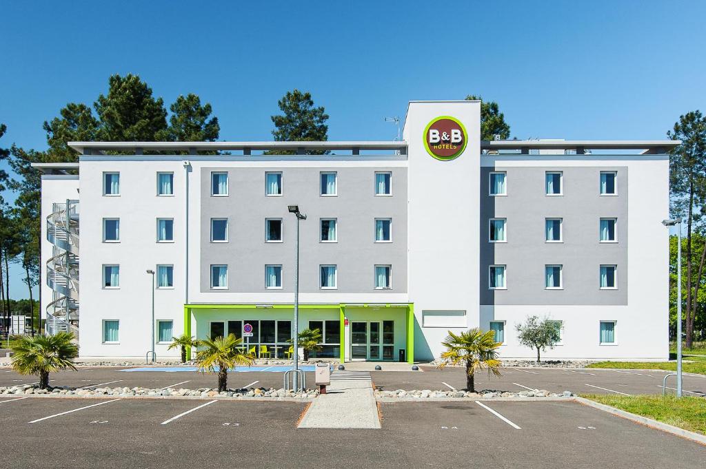 Saint-AvitB&B HOTEL Mont-de-Marsan的停车场上标有标志的白色建筑