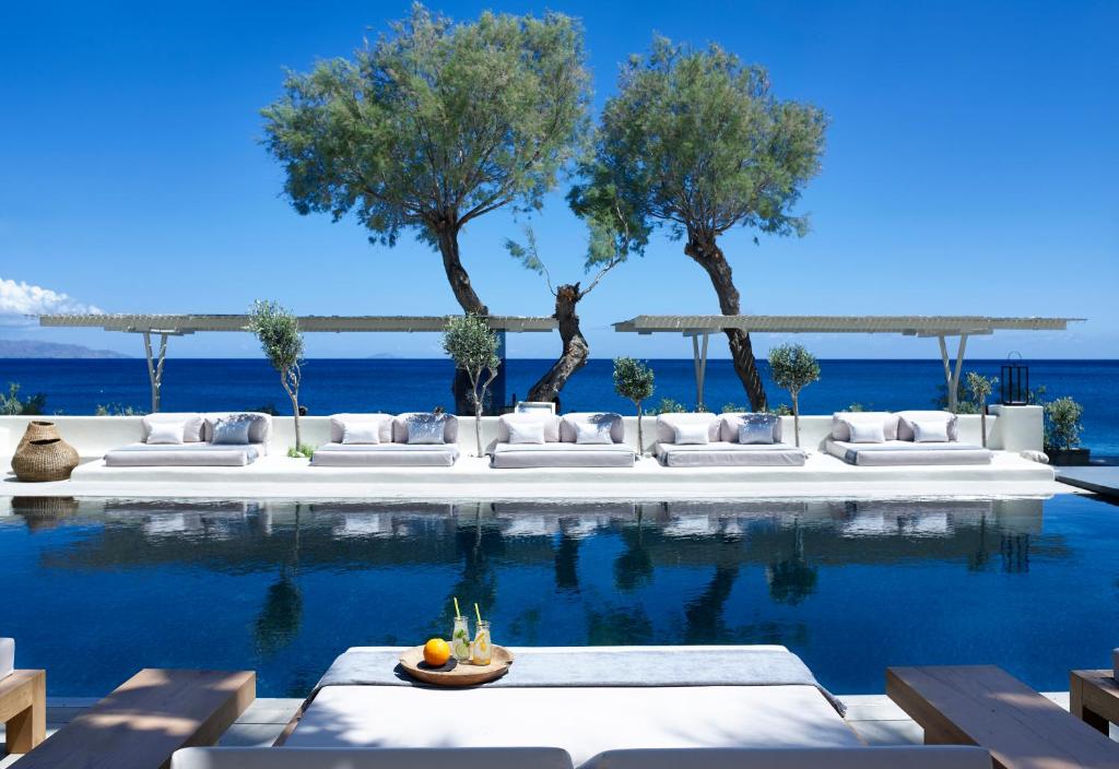 卡马利贝罗尼亚斯别墅的一个带白色沙发、树木和大海的游泳池