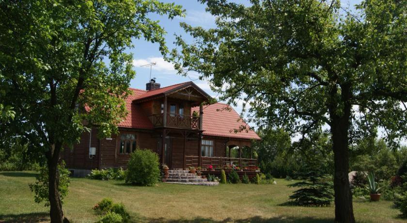 StanisławowoKurpiowska Chatka的田野上红色屋顶的木屋
