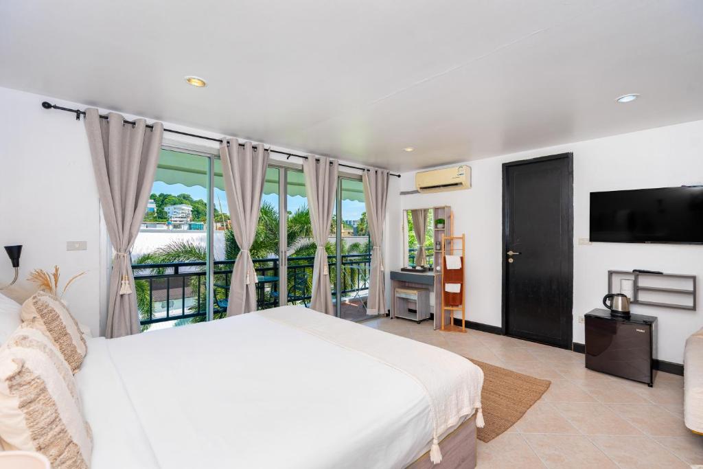 卡塔海滩Kata Station Boutique Hotel的一间带白色床的卧室和一个阳台