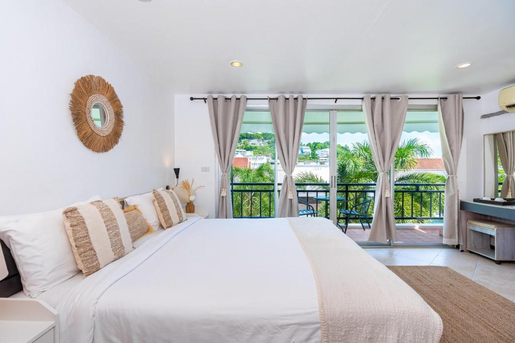 卡塔海滩Kata Station Boutique Hotel的白色卧室设有一张大床和一个阳台