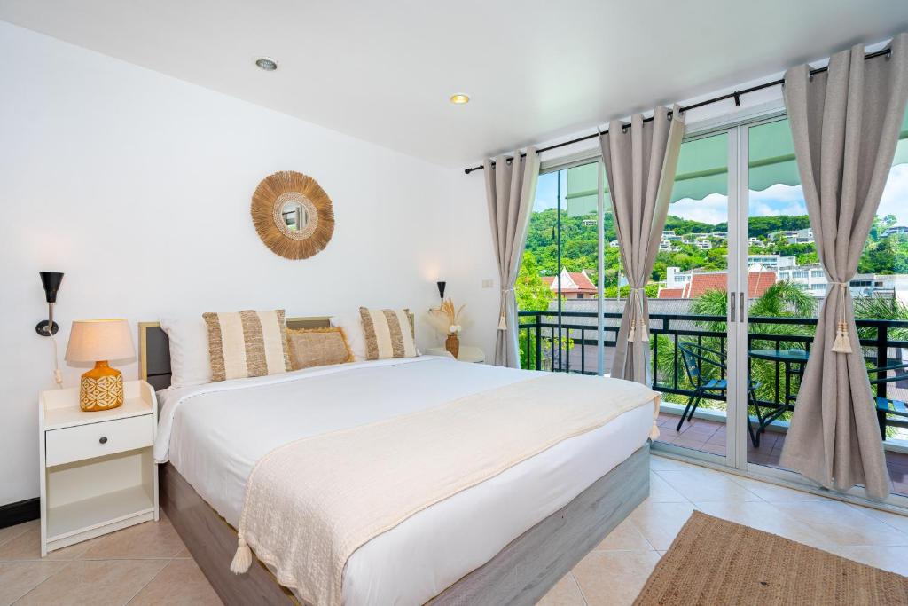 卡塔海滩Kata Station Boutique Hotel的一间带床和阳台的白色卧室