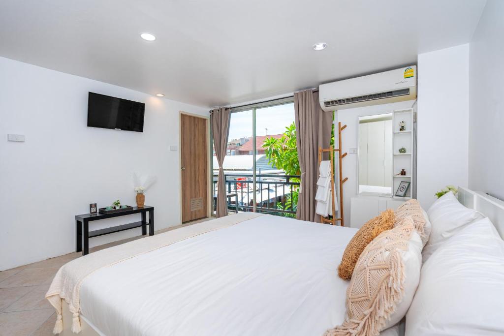 卡塔海滩Kata Station Boutique Hotel的一间带大床和电视的白色卧室