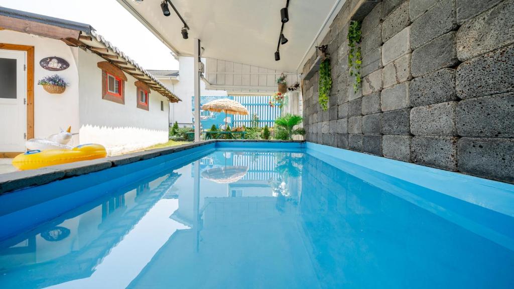 江陵市Gangneung ggabinejip hanok pension的房子里有蓝色水的游泳池