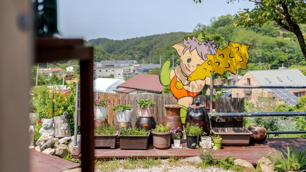 江陵市Gangneung ggabinejip hanok pension的一个种着盆栽植物的花园，栅栏上挂着一块牌子
