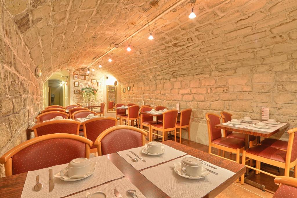 巴黎121巴黎酒店的一间带桌椅和石墙的餐厅