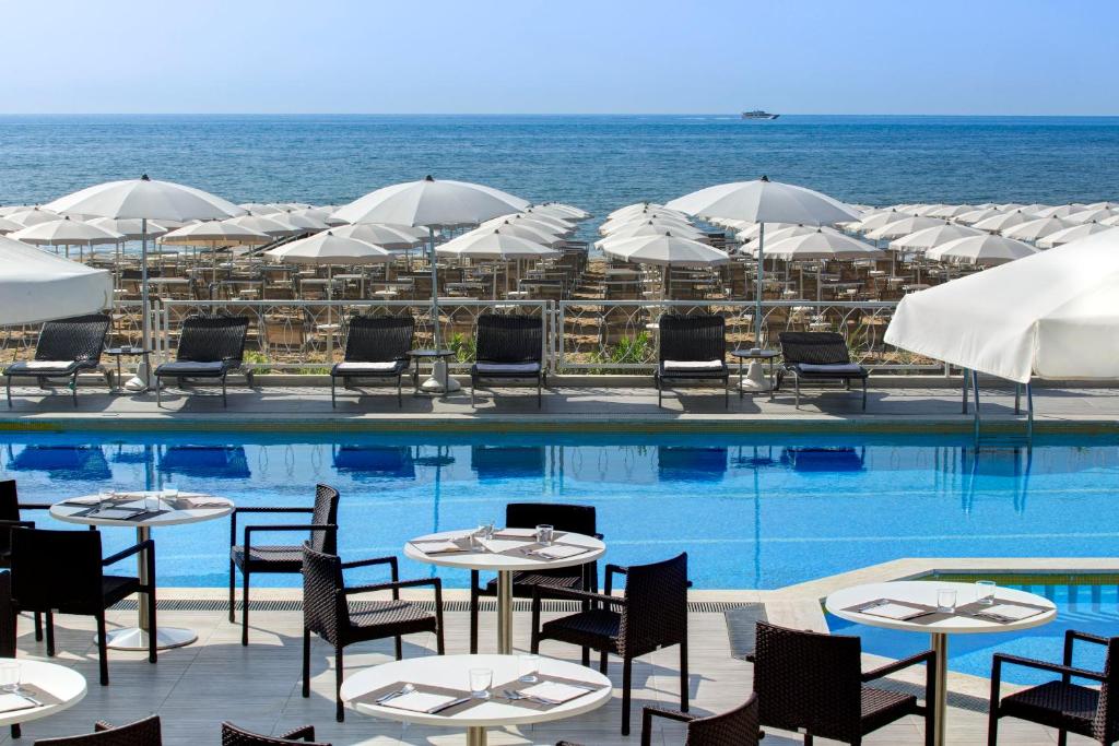 利多迪耶索罗拜伦贝拉维斯特酒店的一个带桌椅和遮阳伞的游泳池