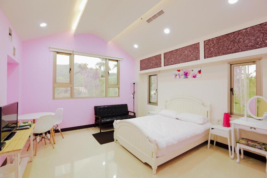 三义乐福民宿的卧室设有粉红色的墙壁、一张床和一张书桌