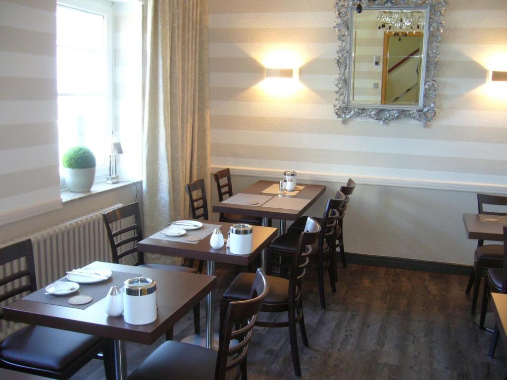古梅尔斯巴赫塞利加尔尼酒店的餐厅设有木桌、椅子和镜子