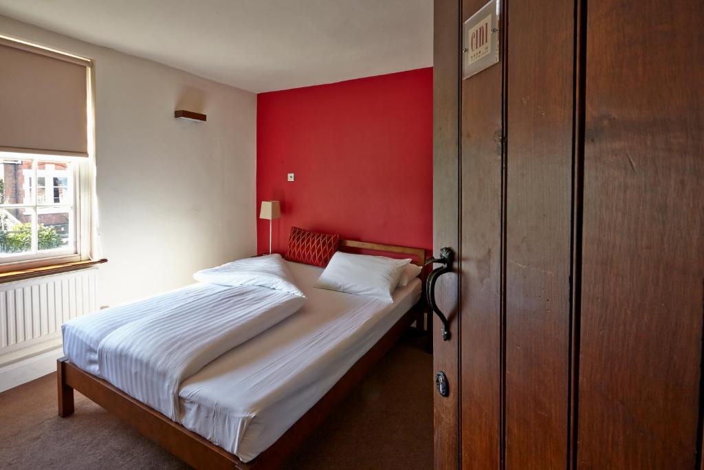 莱斯特奇妮酒店的一间卧室配有一张红色墙壁的床