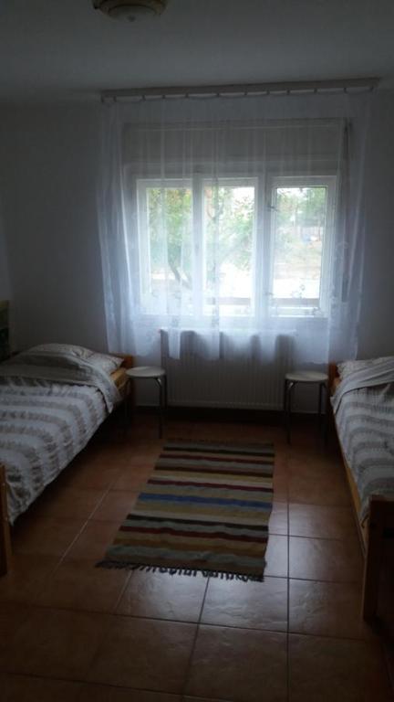莫劳豪洛姆Hetedhét Vendégház的一间卧室设有两张床、一个窗户和一个地毯。