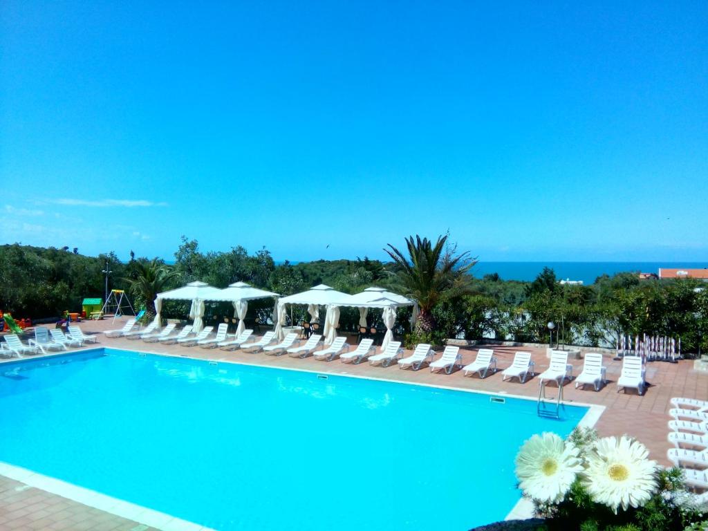 维耶斯泰贝拉维斯塔俱乐部酒店的一个带椅子和遮阳伞的游泳池以及大海