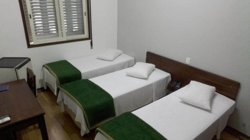 卡萨帕瓦Arcadas Hotel的客房设有两张床、一张桌子和一扇窗户。