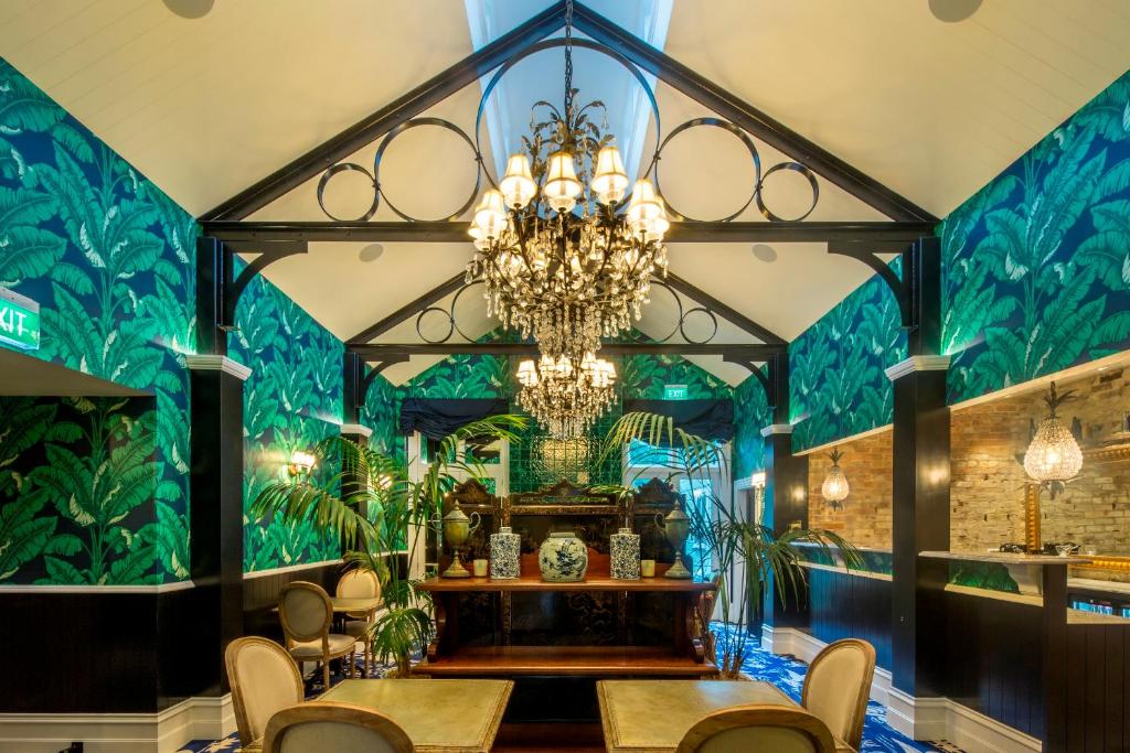 皇后镇Hulbert House Luxury Boutique Lodge Queenstown的一间设有吊灯和绿色墙壁的用餐室