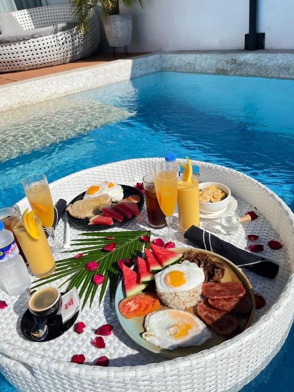 道伊斯Epic Suites Bohol ADULTS ONLY的游泳池旁边的早餐托盘里有鸡蛋和水果