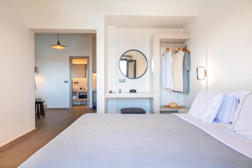伊亚North Wind Luxury Suites的卧室里有一张白色的床和一面镜子
