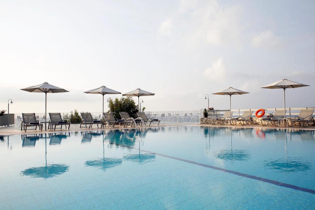 斯卡拉Asteris Hotel的一个带椅子和遮阳伞的大型游泳池