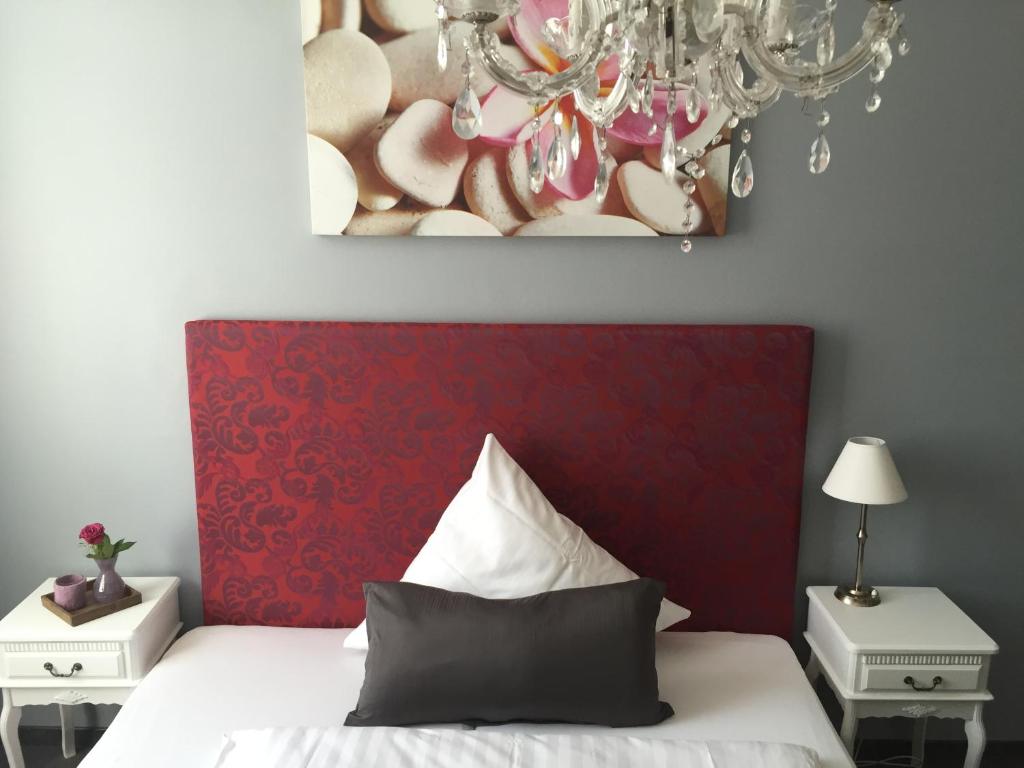 美因河畔法兰克福海德黑姆酒店的一间卧室配有一张带红色床头板和吊灯的床。