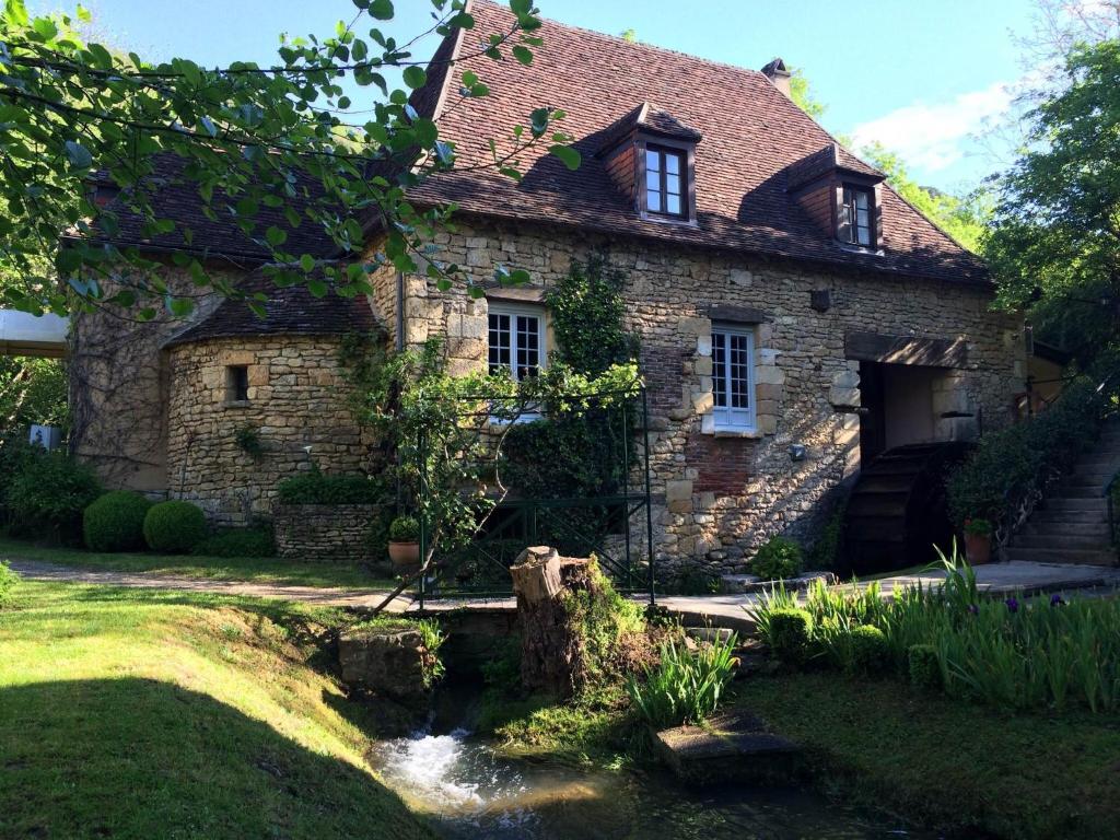 莱塞齐耶德泰阿克Le Moulin De La Beune的一座古老的石头房子,前面有一条小溪