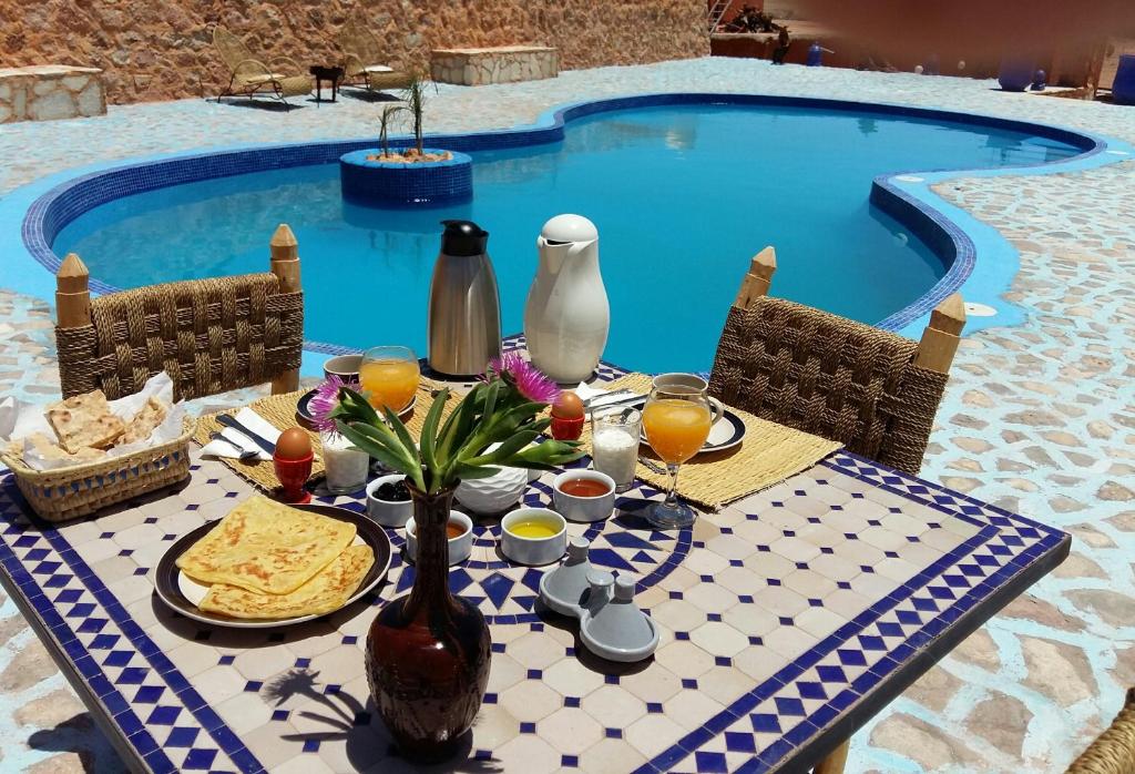 阿伊特本哈杜Riad Paradise of Silence的游泳池旁的餐桌,供应食物和饮料
