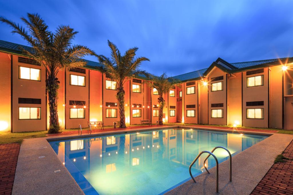 甲万那端甲万那端温德姆麦克罗特酒店的棕榈树建筑前的游泳池
