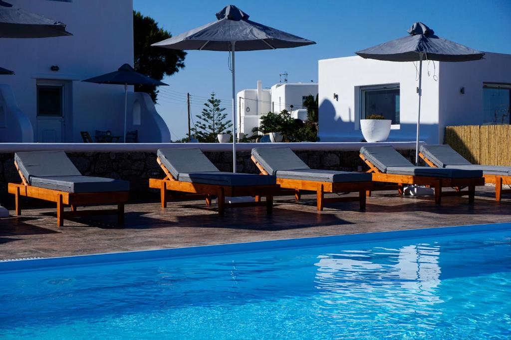 格拉斯托斯Casa Nostra Mykonos Boutique Rooms & Studios的游泳池旁的游泳池配有椅子和遮阳伞