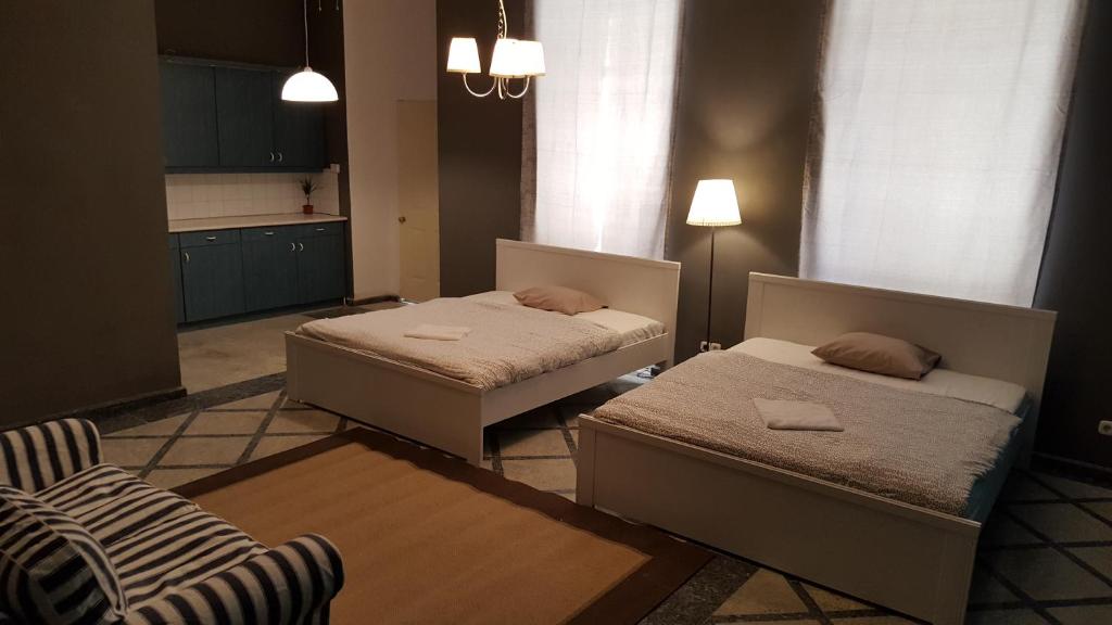 布达佩斯普瑞梅尔公寓旅馆的一间卧室配有两张床和椅子