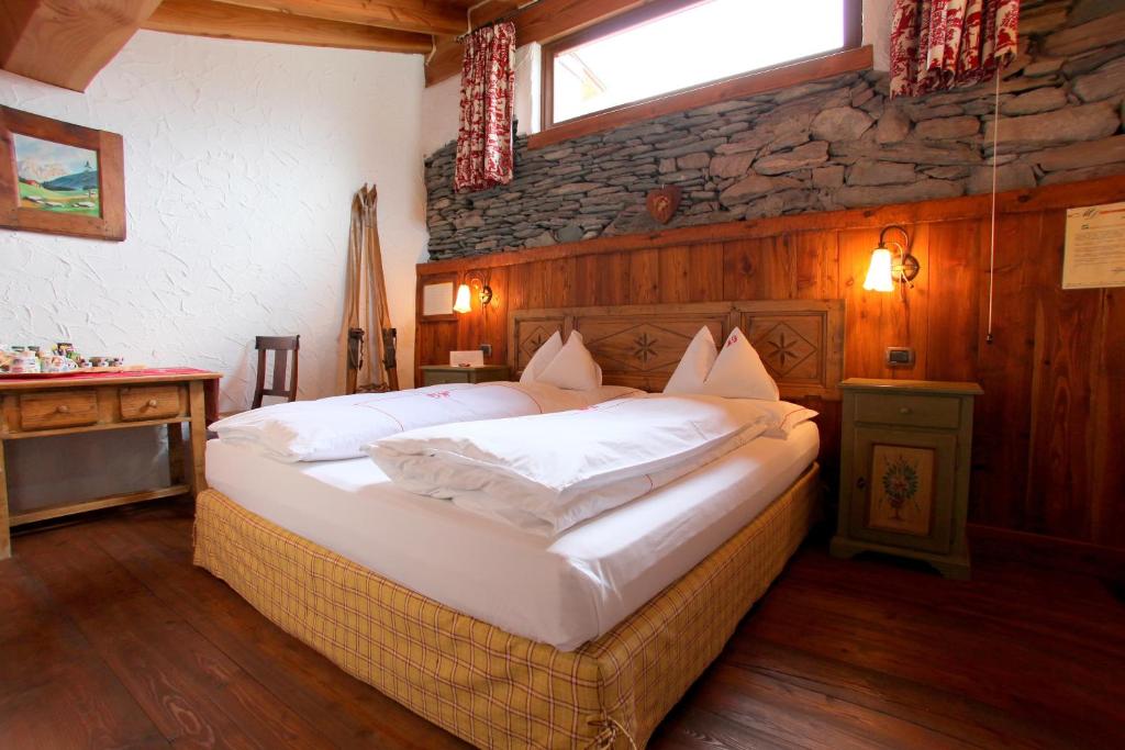 查兰德圣安塞尔Eco Chalet Maison Dominique的一间卧室设有一张带石墙的大床
