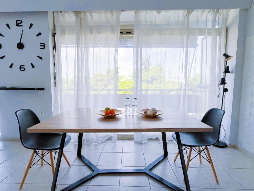 雅典Spacious 2BR by Floisvos Beach Saltwater Balcony的餐桌、椅子和墙上的时钟