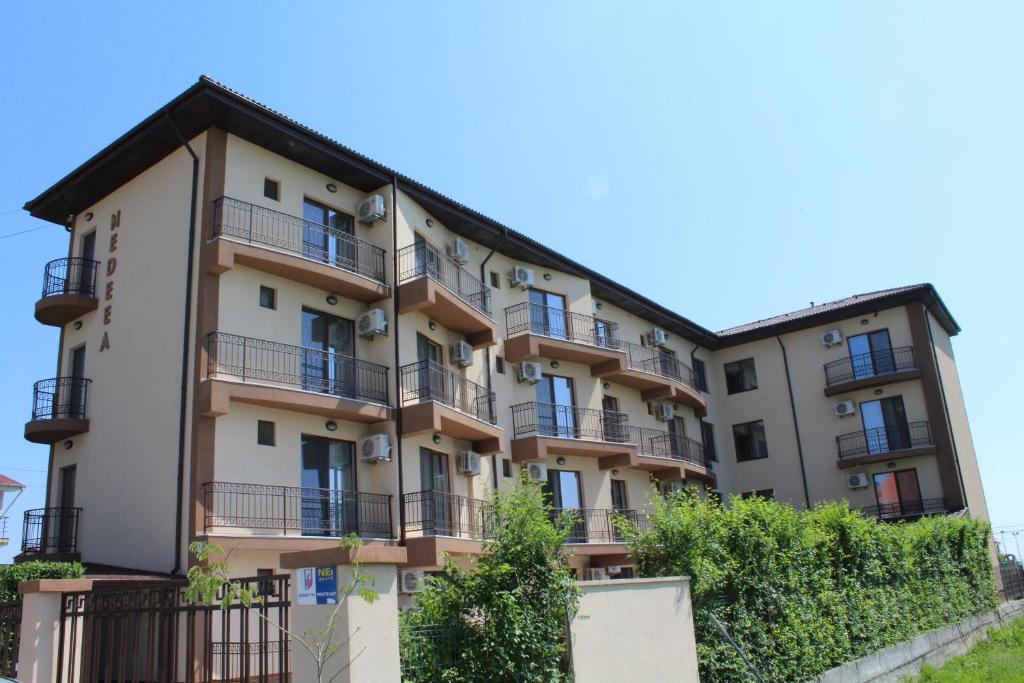 科斯蒂内什蒂Vila Medeea的公寓大楼设有阳台和树木