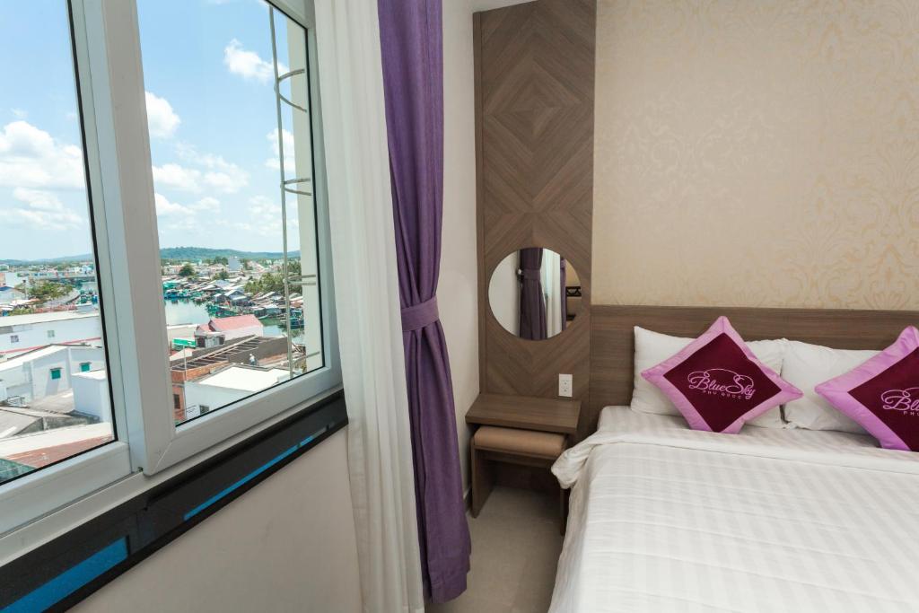 富国蓝天富国酒店的一间卧室设有两张床和大窗户