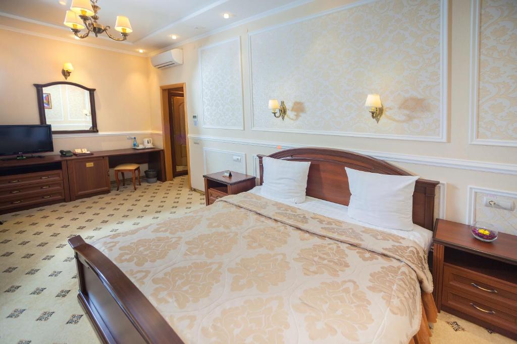 库尔斯克名誉酒店 的一间卧室配有一张床、一张书桌和一台电视
