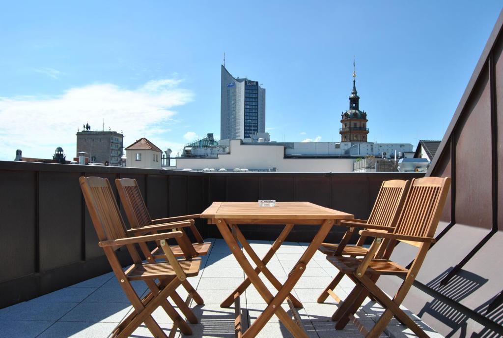 莱比锡特拉福德天空公寓的阳台上配有一张木桌和四把椅子
