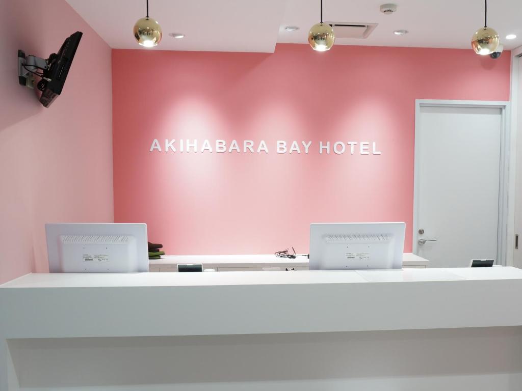 东京秋叶原湾胶囊旅馆（只限女性）的粉红色的房间,柜台上有两台电脑