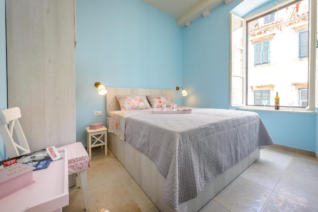 杜布罗夫尼克Stradun View En Suite Rooms & Studio的蓝色的卧室设有床和窗户