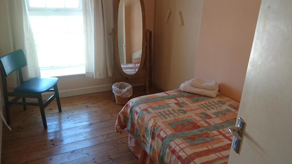波特马吉Eilymaes的一间卧室配有一张床、一把椅子和镜子