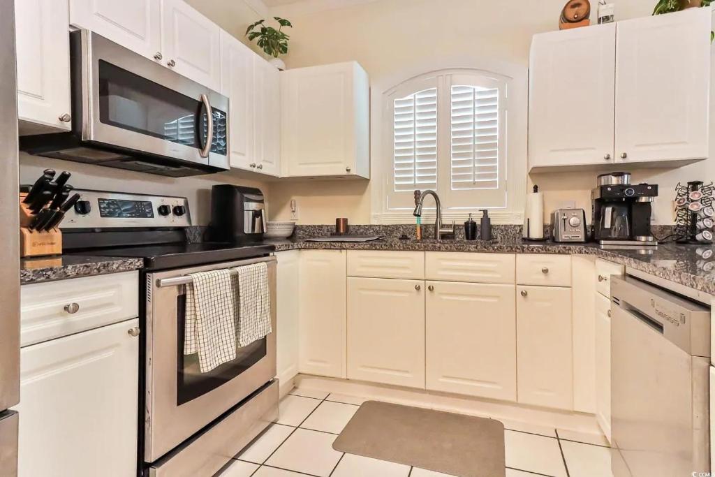 默特尔比奇Beautiful 1500 s f 3 Bd - 2 Ba condo overlooking stream and golf course的配有白色橱柜和黑色家电的厨房