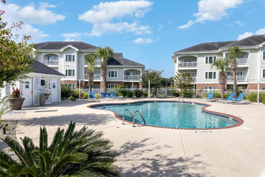 默特尔比奇Beautiful 1500 s f 3 Bd - 2 Ba condo overlooking stream and golf course的两栋大房子前面的游泳池