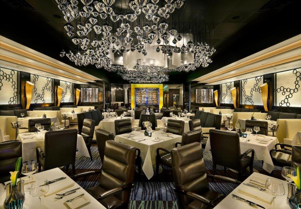 里诺Atlantis Casino Resort Spa的餐厅配有白色的桌椅和吊灯