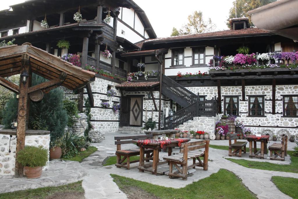 多布里尼什特Family hotel Makedonska Kruchma的前面有桌子和长凳的房子
